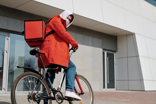 Delivery man with a face mask riding a bicycle
